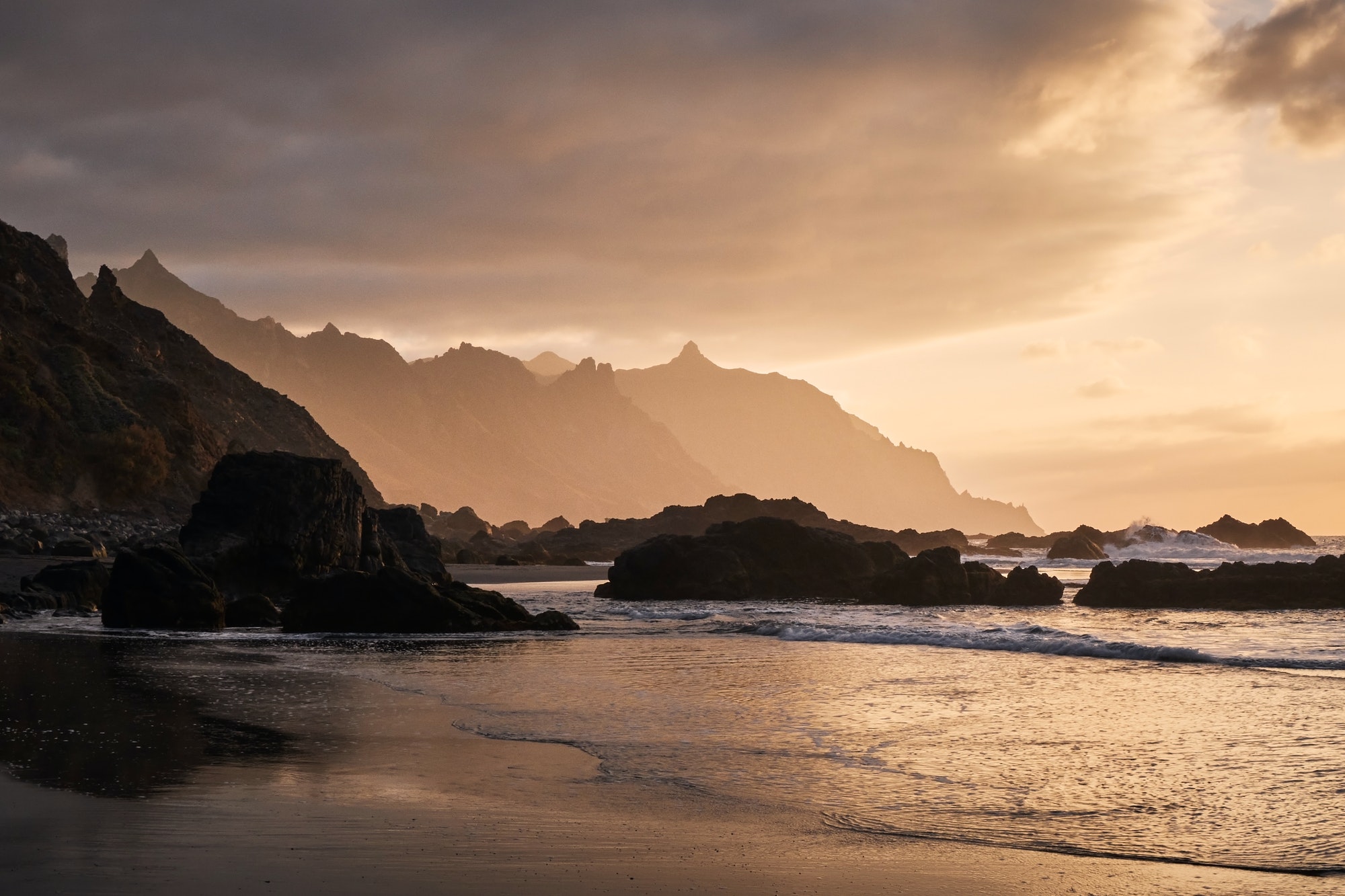 Silhouettes of cliffs on the coast in the golden light of the sunset. Tenerife, Canary Islands.